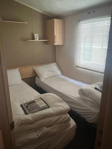 twee bedden in een kleine kamer met een raam bij Lisa and Laddy Caravan Hire in Meliden
