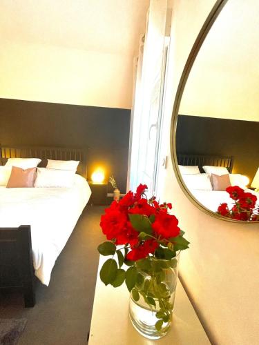 a bedroom with a mirror and a vase with red flowers at LIVABLŌM "Maison et Parking Privée" in Guesnain