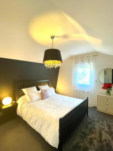 - une chambre avec un grand lit blanc et un lustre dans l'établissement LIVABLŌM 