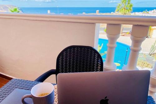 un computer portatile seduto su un tavolo con una tazza di caffè di Golden Suite Ocean View & Pool a Los Cristianos