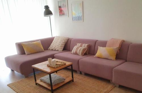 a purple couch in a living room with a table at 't Hoekhuisje in Katwijk aan Zee