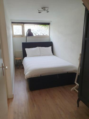 a bed in a small room with a window at 't Hoekhuisje in Katwijk aan Zee