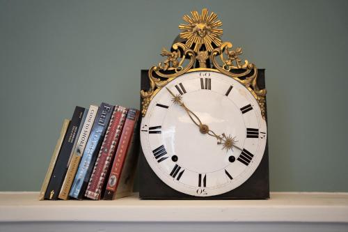 a clock sitting on a shelf next to books at Caffè delle Rose Les Chambres in Verbania