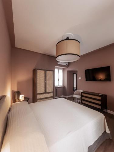 a bedroom with a large white bed and a television at Caffè delle Rose Les Chambres in Verbania