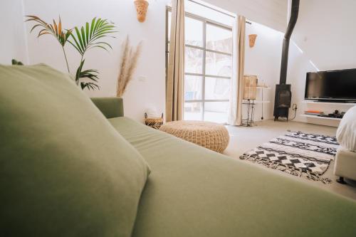 a living room with a green couch and a large window at Sol Ramon boutique hotel in Mitzpe Ramon