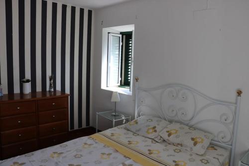 ein Schlafzimmer mit einem Bett, einer Kommode und einem Fenster in der Unterkunft Casa de Alpalhão in Alpalhão