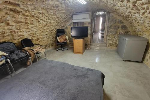 um quarto com uma parede de pedra, uma cama e uma televisão em historic luxury cave em Jerusalém