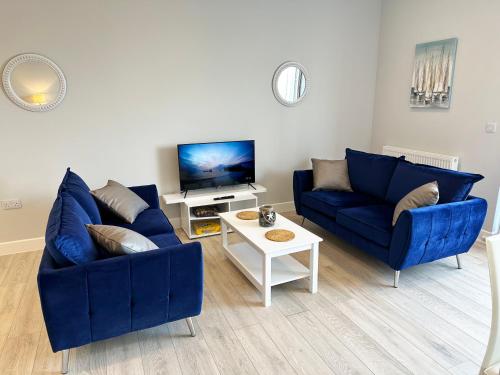 a living room with two blue couches and a tv at Ocean View Suite - Near Hythe - On Beach Seafront - Private Parking in Dymchurch