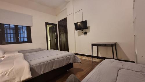 a bedroom with two beds and a table and a television at Nuevo Hotel Aramaya in Montevideo