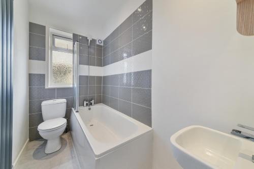 a bathroom with a toilet and a tub and a sink at Bromley Palace - Entire 2 Bed House - Free Parking - Self Check-in in London