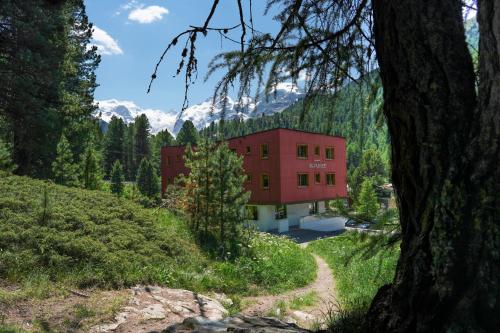 a red building in the middle of a forest at Hotel Morteratsch in Pontresina