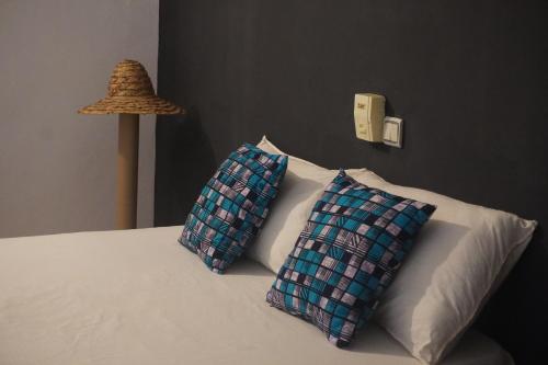 two pillows sitting on a bed next to a lamp at Au cœur de Ouidah 2 in Ouidah