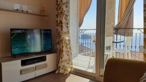 a living room with a television and a balcony at Apartments Relax in Utjeha