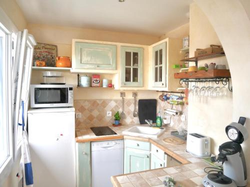 a kitchen with a white refrigerator and a sink at La Caravelle Vue Mer et Wifi in Le Lavandou