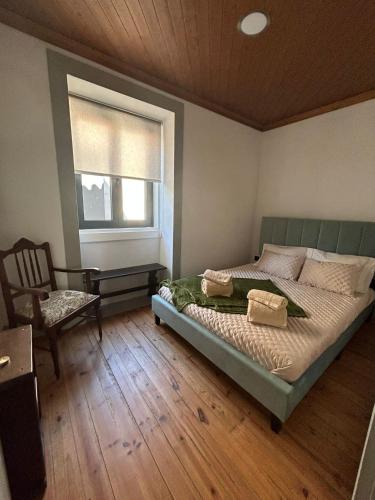 a bedroom with a bed and a window and a chair at Domus Vila Maria Douro in Castanheiro do Sul
