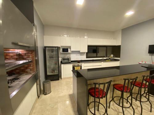 a kitchen with white cabinets and red chairs at a counter at Casa del Sol in Salta