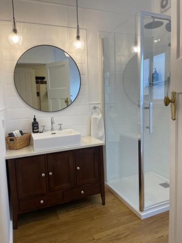 a bathroom with a sink and a shower with a mirror at Old Maffra Cottage in Maffra