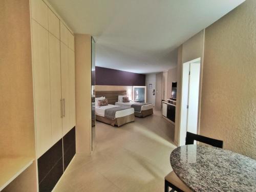 a hotel room with a bed and a living room at Hotel Metrópole Maringá in Maringá