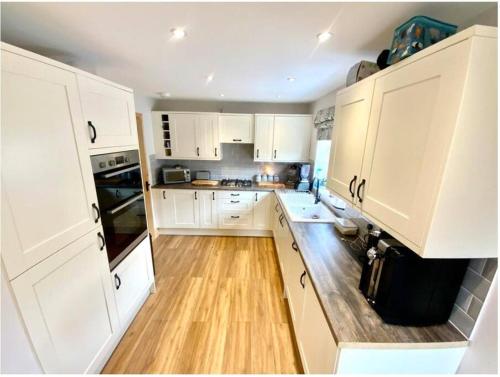 a kitchen with white cabinets and a wooden floor at Ty Gwyn in Prestatyn