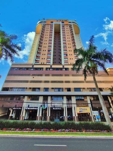 a tall building with a palm tree in front of it at Hotel Metrópole Maringá in Maringá