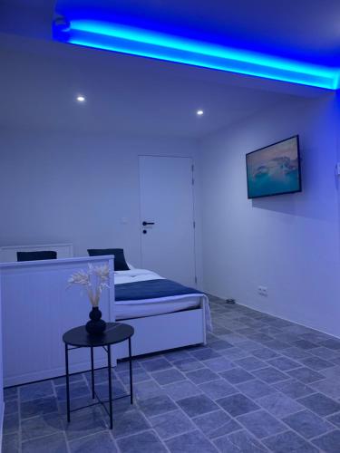 Cette chambre comprend un lit et une table avec une lumière bleue. dans l'établissement Residentie Don, à Bruges