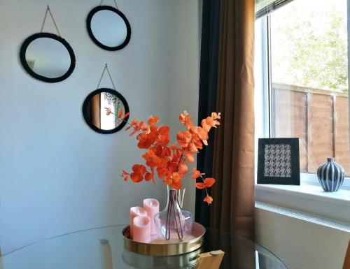 un vase avec des fleurs orange sur une table en verre avec des miroirs dans l'établissement 2 Bedroom House in Quiet Area, Close to M5 With Free Parking by Glos Homes Ltd, à Gloucester