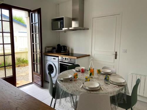 a kitchen with a table and chairs and a kitchen with a table and a table at La Maison Cabourgeaise proche mer in Cabourg