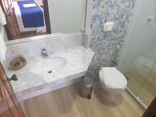a bathroom with a sink and a toilet at Pousada Ilha Bella in Guriri