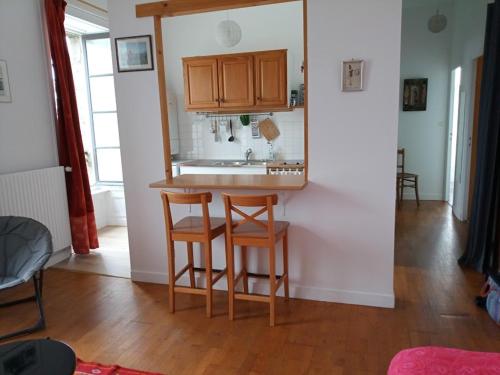 a kitchen with a counter and two chairs and a mirror at Gîte du port Rhu in Douarnenez