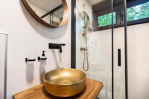 baño con lavabo de oro en una encimera de madera en Tree Elements treehouse retreat, en Slunj