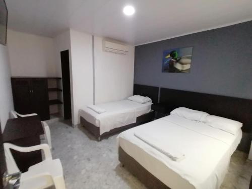 a hotel room with two beds and a chair at Hotel Bucare in Yopal