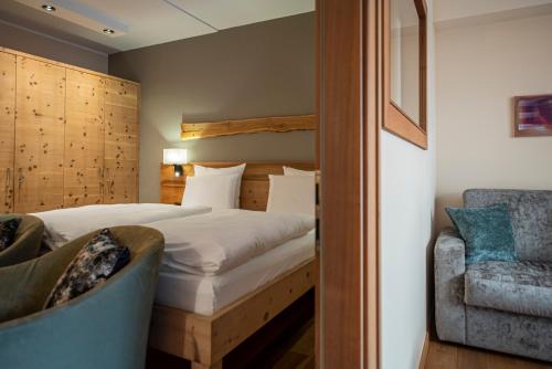a hotel room with a bed and a chair at Vitalpina Hotel Waldhof in Rablà