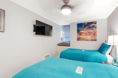 a bedroom with two blue beds and a tv at Berni's Ocean View Castle - an Oceanside Legend in Oceanside