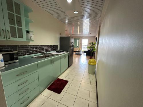eine Küche mit grünen Schränken und Fliesenboden in der Unterkunft Southside Apartments in Paramaribo