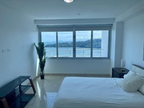 1 dormitorio con cama blanca y ventana grande en 17E Beautiful 2-Bedroom Ocean View Apartment, en Playa Bonita Village