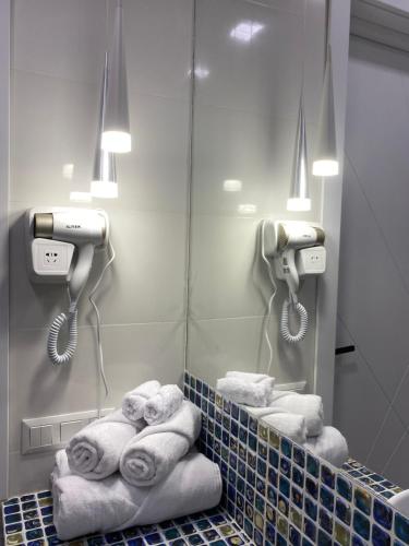 a bathroom with towels and a mirror and lights at City Heart Luxury Apartment in Kutaisi