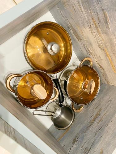 three copper pots and pans sitting on a table at City Heart Luxury Apartment in Kutaisi