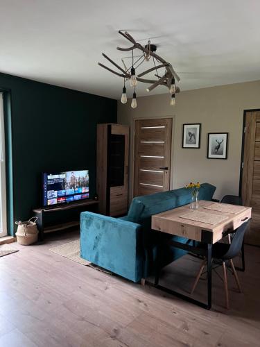a living room with a blue couch and a table at Jeżówka i Sudetka in Jeżów Sudecki