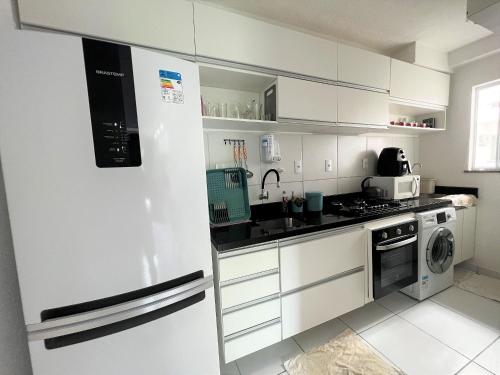 a white kitchen with a refrigerator and a sink at Lua Nova - Vog Acqua Apt na Praia dos Milionários in Ilhéus