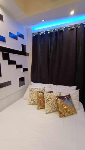een slaapkamer met een wit bed met gouden kussens bij The Pod by M&C in Manilla