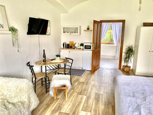 ein Wohnzimmer mit einem Tisch und einer Küche in der Unterkunft Apartmán v koňském areálu Židovice in Louny