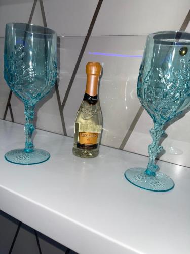 two blue glasses and a bottle of wine on a shelf at Alex mary home in Naples