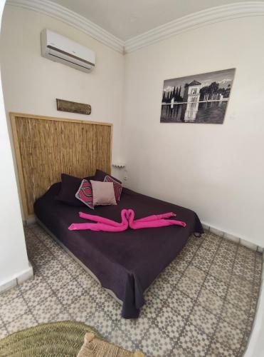 Un dormitorio con una cama con pantalones rosados. en Riad Bab Lakhmiss, en Marrakech