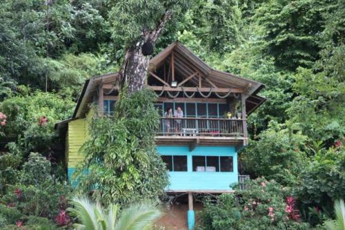a house with people standing on the balcony of it at Ecolodge el Arca Bahia Solano in Bahía Solano
