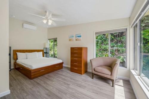 a bedroom with a bed and a chair and windows at @ Marbella Lane - Sunshine Seascape Ocean View in Kaneohe