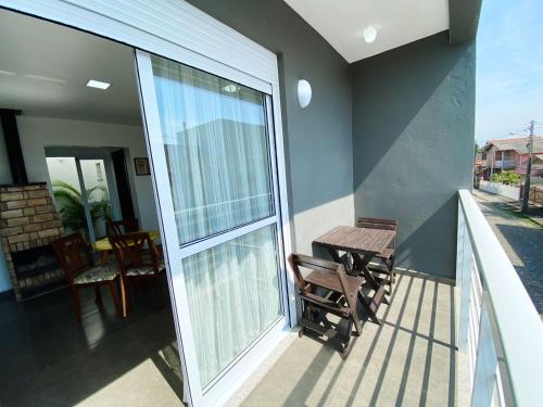 a balcony with a table and chairs and a large window at Sobrados Molhes in Passo de Torres