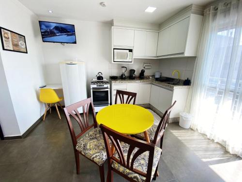 a kitchen with a yellow table and chairs at Sobrados Molhes in Passo de Torres