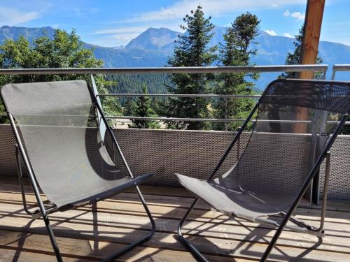 two chairs on a deck with mountains in the background at Arolles D21 - Chamrousse 1700 - Les Villages du Bachat in Chamrousse