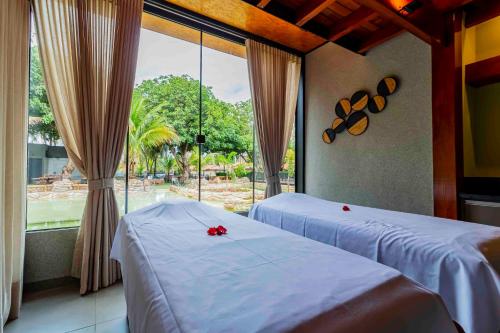 two beds in a room with a large window at Carpe Diem Eco Resort & SPA in Olímpia