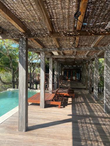 um pavilhão com bancos num deque ao lado de uma piscina em Casa Vive Bacalar em Bacalar